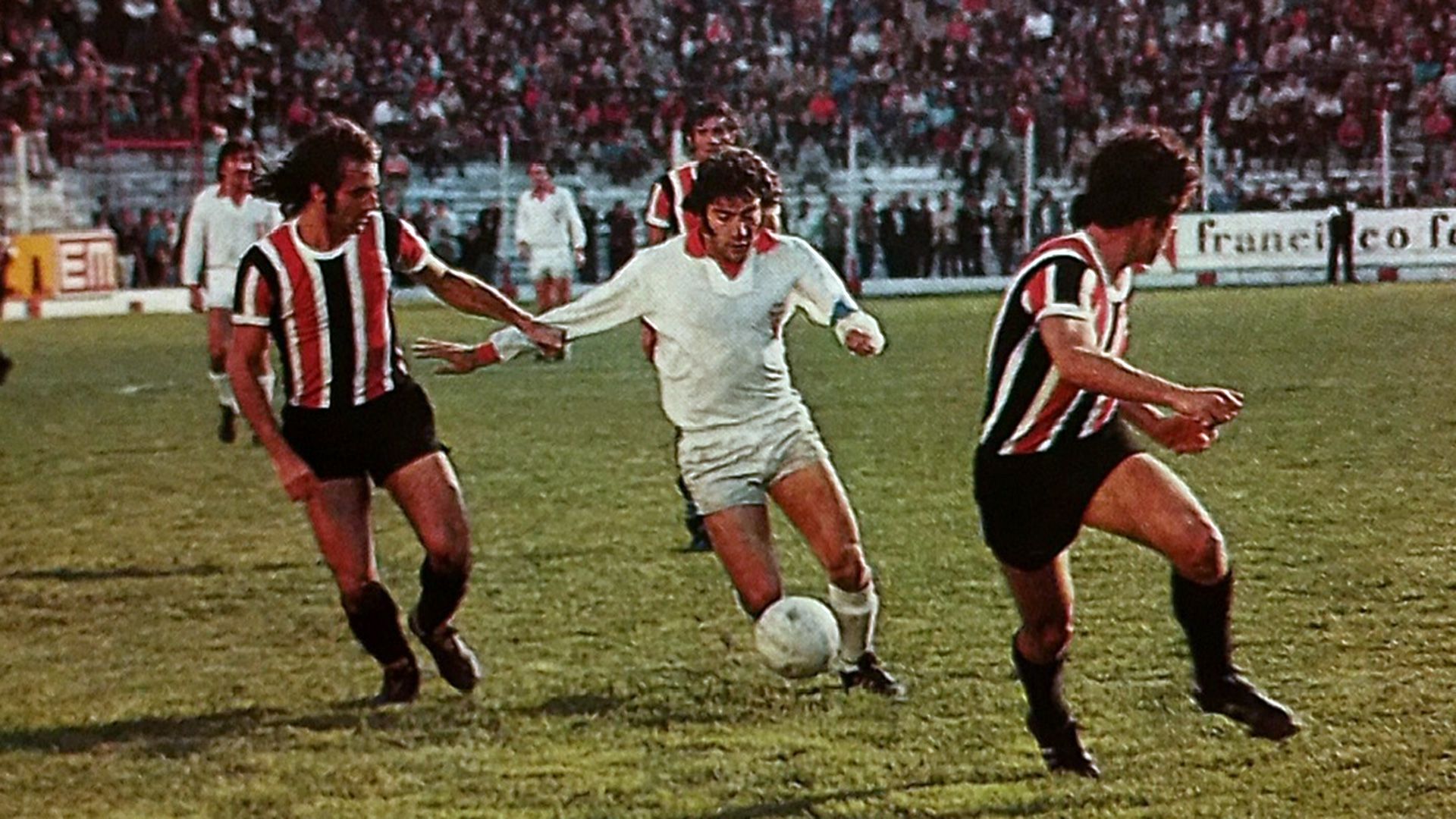 Miguel Ángel Brindisi entre dos jugadores de Chacarita 