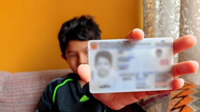 Un menor de edad sostiene su nuevo DNI electrónico, luego de que sus padres hicieran el trámite para cambiar su antiguo documento de identidad color amarillo.